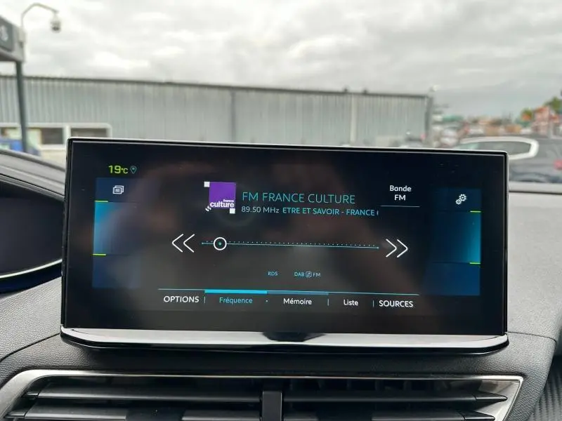 Écran tactile central du tableau de bord du Peugeot 3008 Hybride Rechargeable noir, affichant une radio FM.