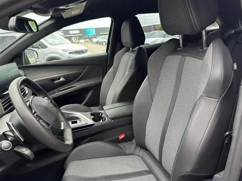 Vue intérieure côté conducteur du Peugeot 3008 Hybride Rechargeable 2024, sièges tissu et cuir noir avec volant multifonction.