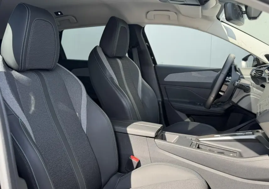 Vue intérieure côté droit de la Peugeot 308 SW 2025, sièges avant en sellerie tri matières noire avec surpiqûres bleues.