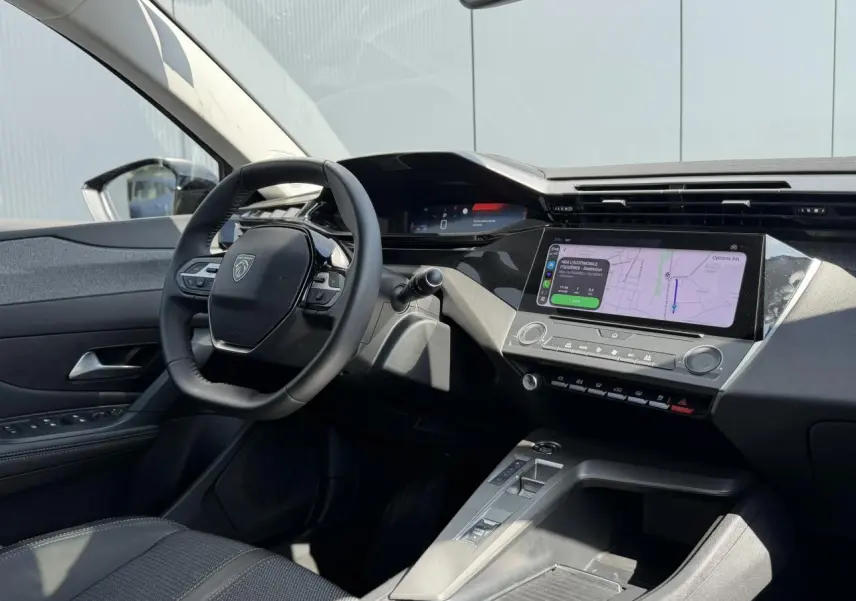 Vue intérieure côté conducteur du Peugeot 308 SW 2025 noir Perla, avec tableau de bord moderne et écran tactile central affichant la navigation.