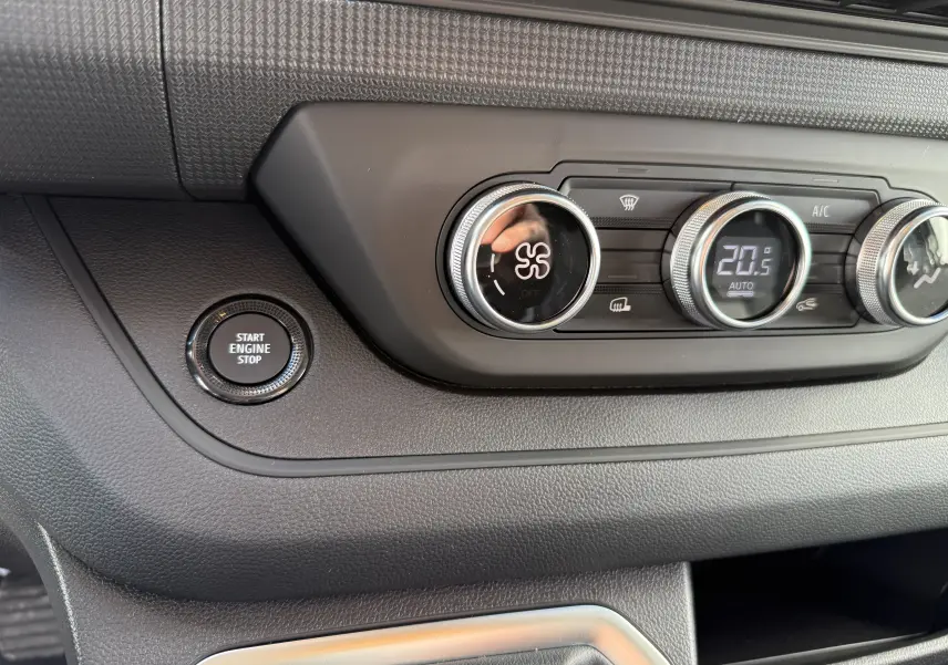 Détail intérieur du tableau de bord du Renault Trafic Fourgon noir, montrant les commandes de climatisation et le bouton start/stop.