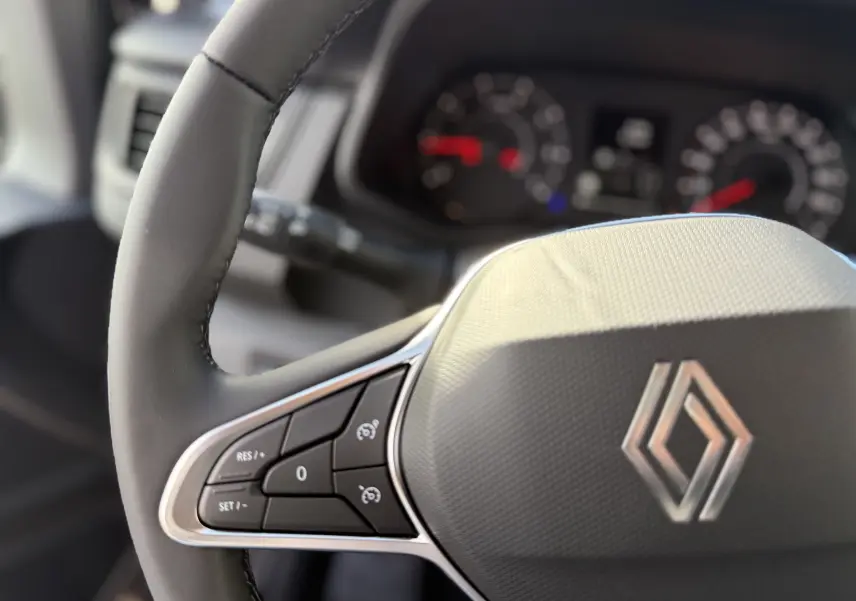 Gros plan sur le volant du Renault Trafic Fourgon 2025, montrant les commandes de régulateur de vitesse.