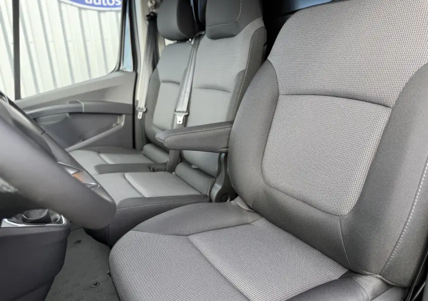 Gros plan sur les sièges avant gris tissu du Renault Trafic Fourgon noir crépuscule, vue depuis le côté gauche intérieur.
