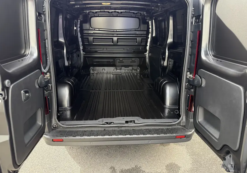 Vue arrière du Renault Trafic Fourgon noir crépuscule avec portes ouvertes montrant l’espace de chargement vide et spacieux.