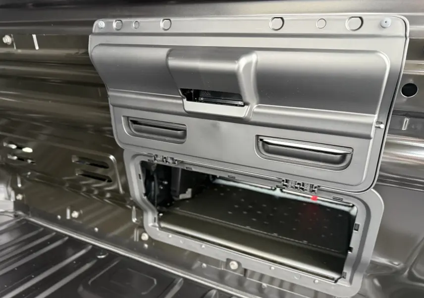 Détail intérieur du Renault Trafic Fourgon noir crépuscule montrant un compartiment de rangement ouvert dans la cloison arrière.