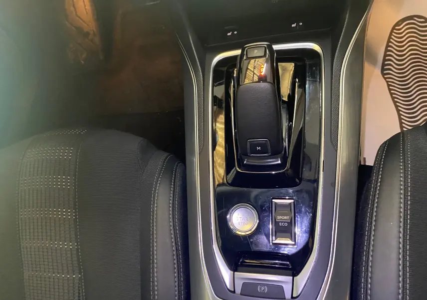 Vue plongeante sur la console centrale noire et levier de vitesse de la Peugeot 308 Allure blanche de 2020.