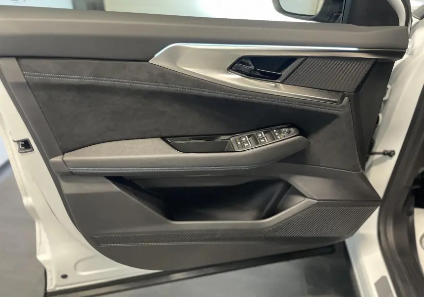 Gros plan sur la porte avant gauche du Renault Austral blanc nacré satin, avec garniture Alcantara et commandes électriques.