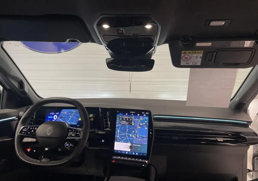 Vue frontale de l'intérieur du Renault Austral 2025, tableau de bord noir avec écran tactile vertical et volant multifonction.