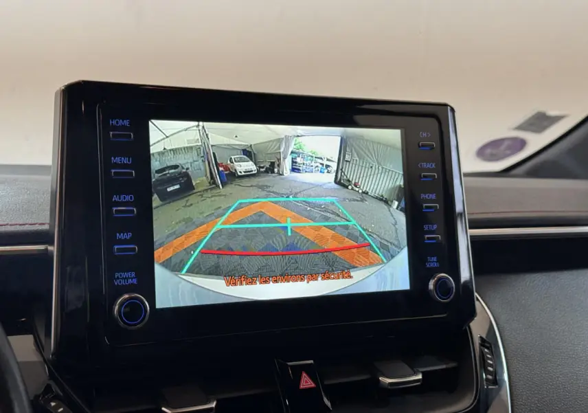Écran tactile central affichant la caméra de recul dans l’habitacle d’une Toyota Corolla Hybride gris clair, vue intérieure frontale.