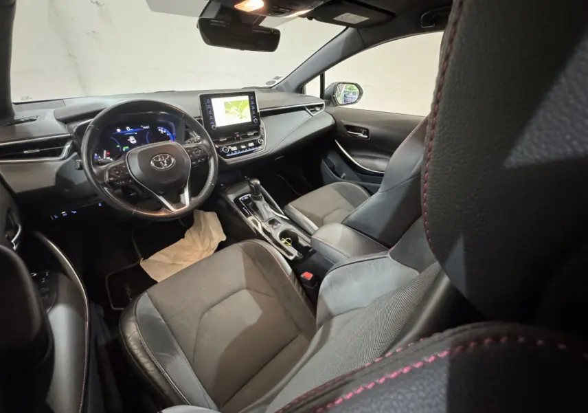 Intérieur de la Toyota Corolla Hybride 122h Collection vu côté conducteur, tableau de bord noir avec écran tactile et volant cuir.