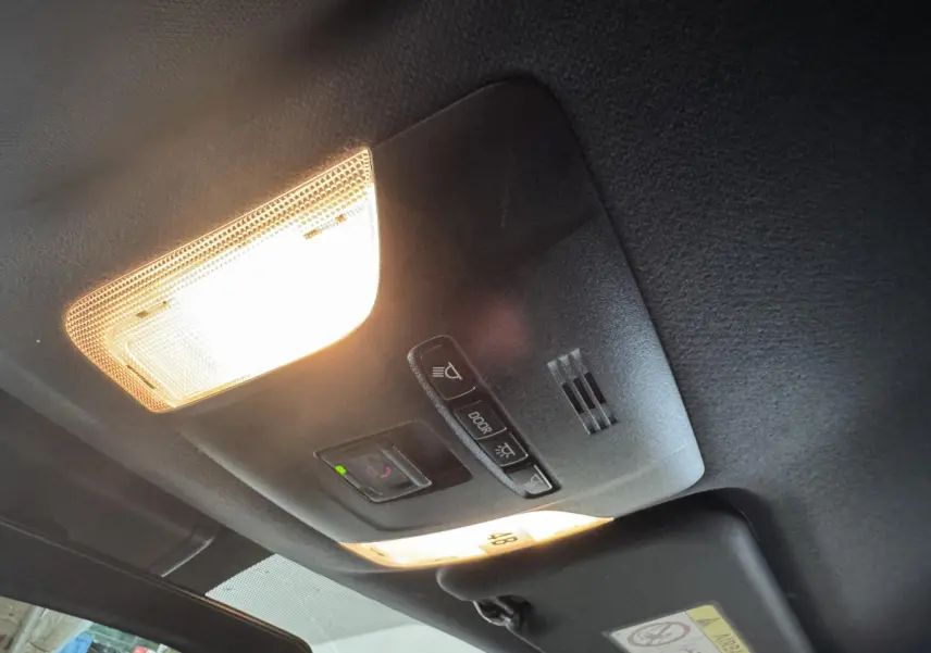 Plafonnier intérieur allumé avec commandes d’éclairage et micro, vue en contre-plongée dans une Toyota Corolla gris clair hybride 2021.