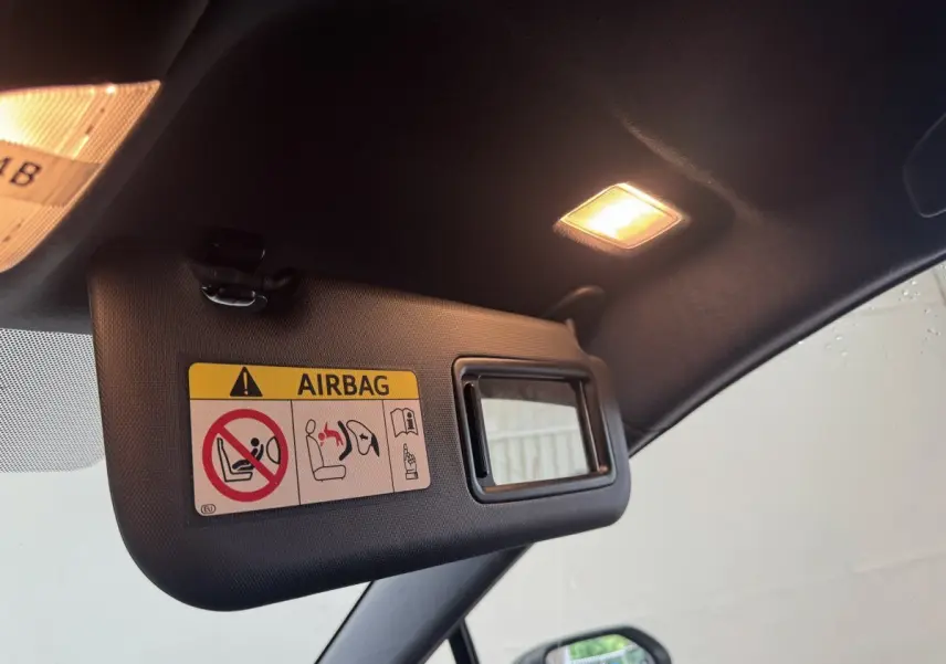 Pare-soleil côté conducteur avec miroir intégré et avertissement airbag dans l'habitacle noir de la Toyota Corolla hybride 2021.