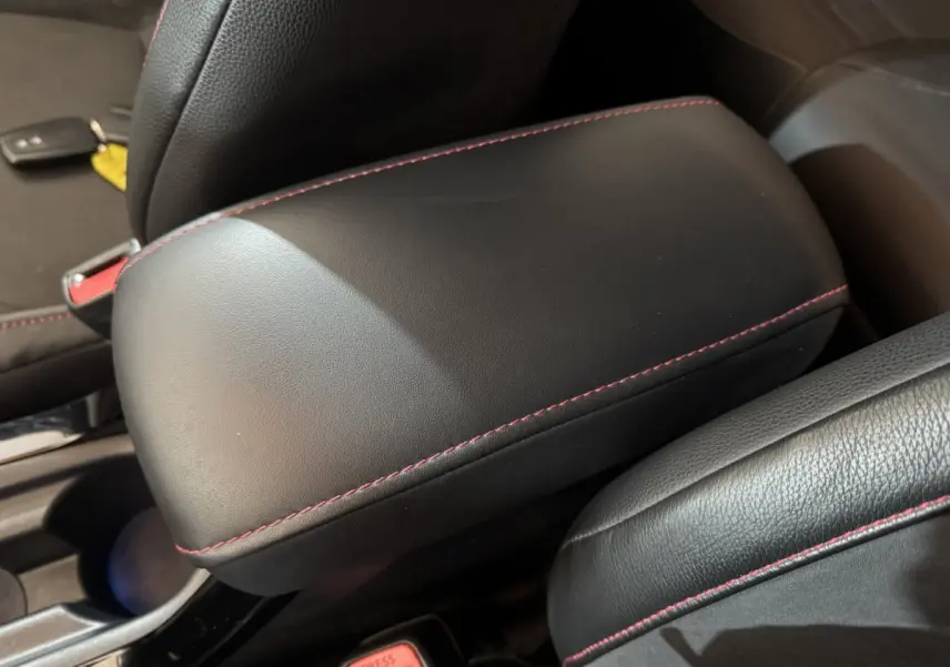 Accoudoir central en cuir noir avec surpiqûres rouges dans l'habitacle de la Toyota Corolla hybride 2021.