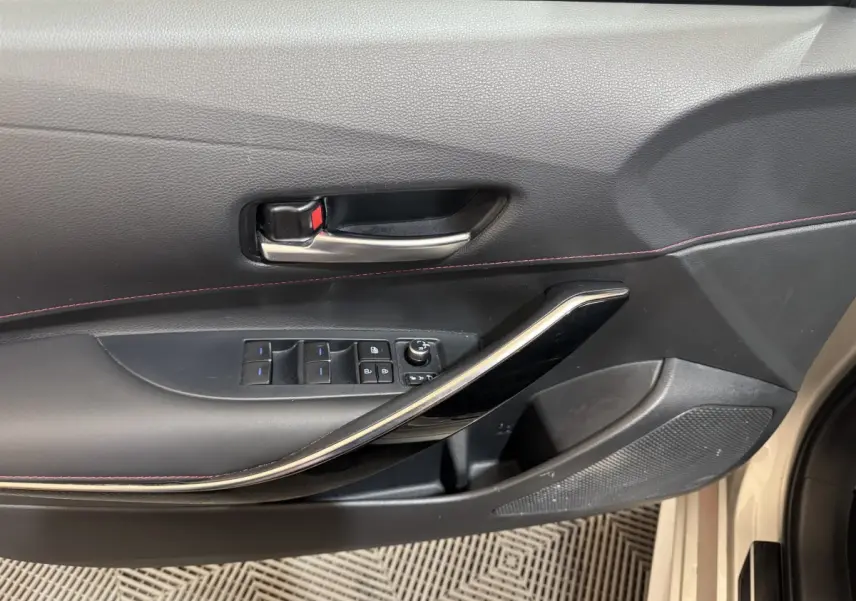 Gros plan sur la porte côté gauche de la Toyota Corolla Hybride 122h Collection 2021, avec commandes vitres et poignée noire.