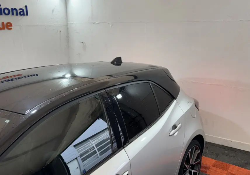 Vue arrière côté droit d'une Toyota Corolla Hybride 122h Collection gris clair avec toit noir brillant et vitres teintées.