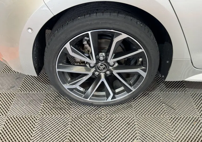 Gros plan sur la roue arrière droite gris clair de la Toyota Corolla Hybride 122h avec jante alliage noire et argentée.