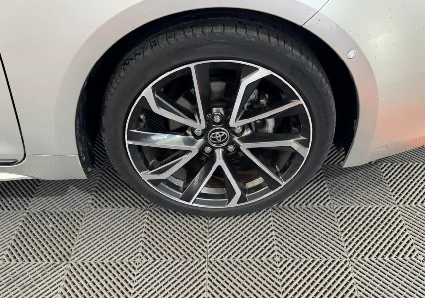 Gros plan sur la roue avant gauche de la Toyota Corolla Hybride 122h Collection gris clair avec jante alliage bicolore.