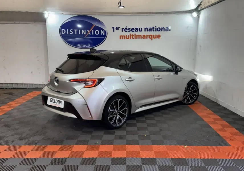Toyota Corolla Hybride 122h gris clair vue 3/4 arrière droit avec toit noir et jantes alliage distinctives