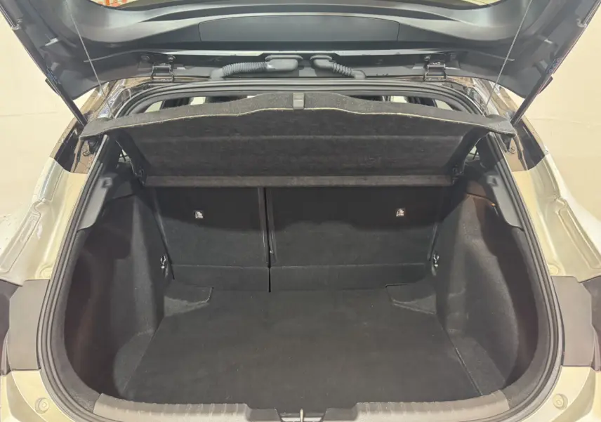 Coffre ouvert vu de l'arrière d'une Toyota Corolla Hybride 122h Collection gris clair, espace de chargement vide et propre.