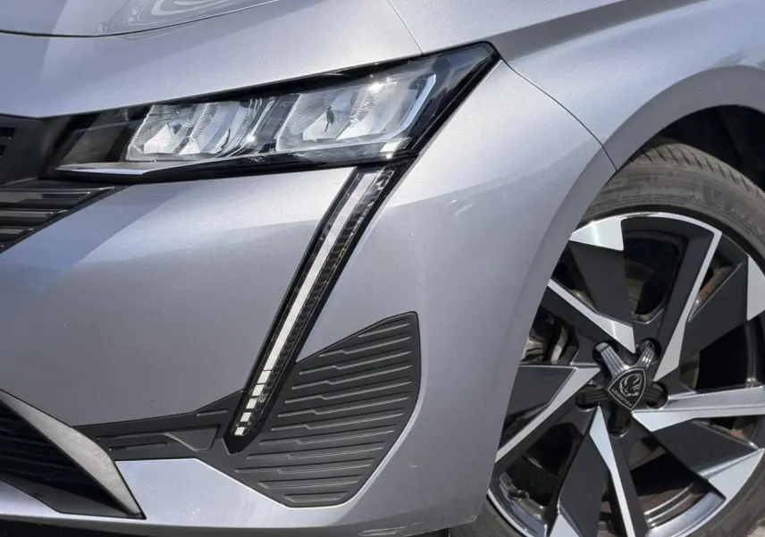 Gros plan sur l’avant droit gris Artense du Peugeot 308 SW 2025, mettant en valeur le phare LED et la jante alliage 17 pouces.