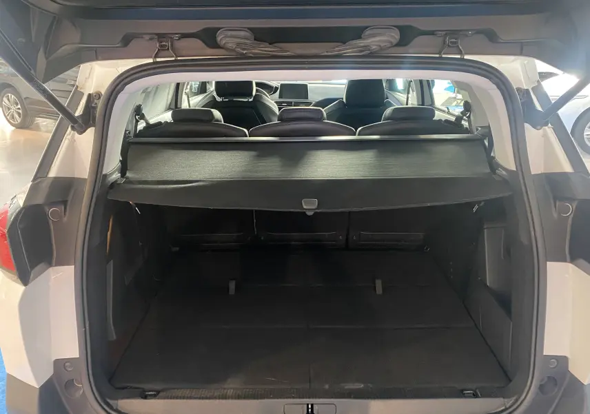 Coffre ouvert d'un Peugeot 5008 blanc blanquise, vue arrière montrant l'espace de chargement et la plage arrière noire.