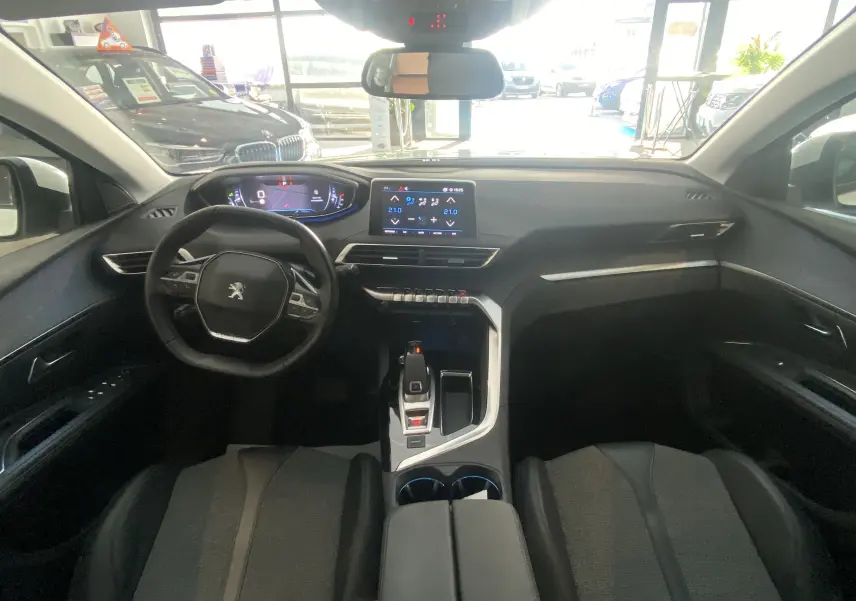 Intérieur du Peugeot 5008 blanc, vue frontale du poste de conduite avec tableau de bord numérique et écran tactile central.