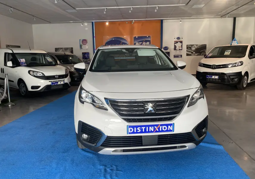 Vue frontale d'un Peugeot 5008 blanc Blanquise exposé en showroom avec plaque Distinxion visible.