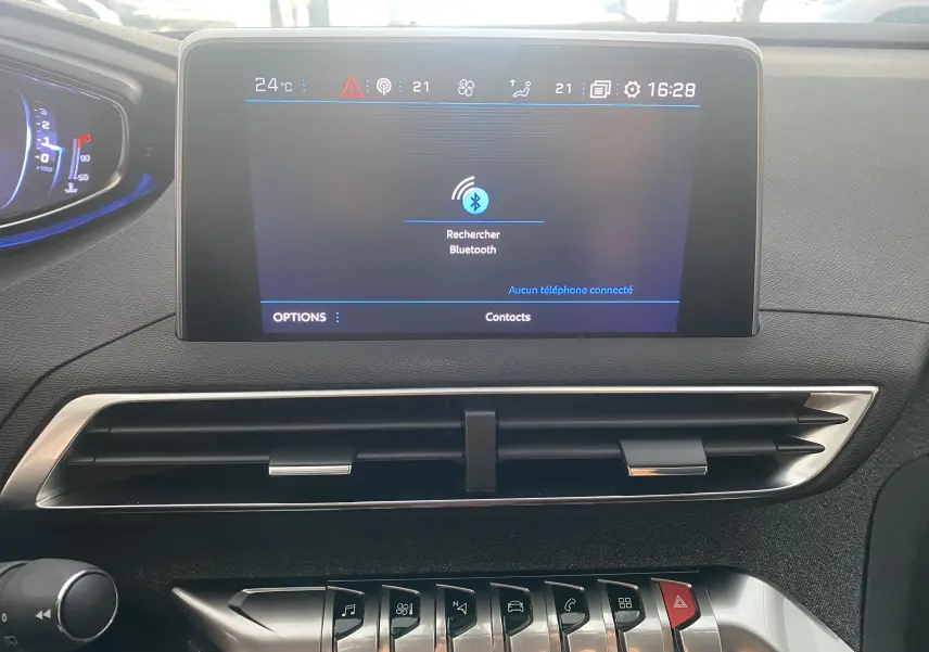 Écran tactile central du tableau de bord du Peugeot 5008 blanc, affichant la recherche Bluetooth et les commandes climatisation.