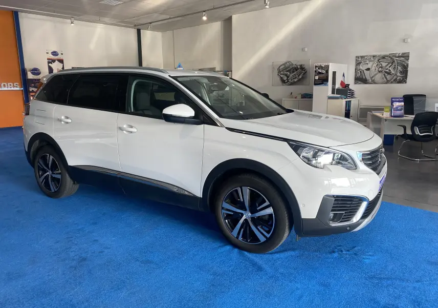Peugeot 5008 blanc blanquise vu en 3/4 avant droit dans un showroom avec jantes noires et attelage neuf.