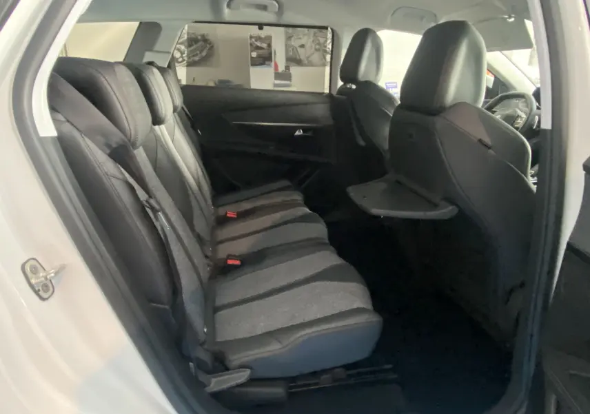 Vue intérieure côté gauche montrant les sièges arrière en tissu gris et cuir noir du Peugeot 5008 blanc.