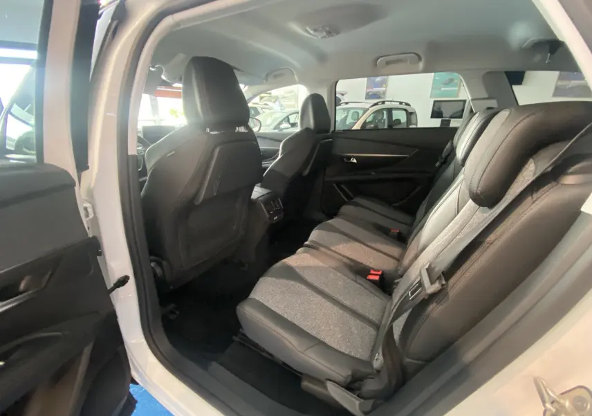 Intérieur arrière du Peugeot 5008 blanc, vue côté gauche montrant les sièges en tissu gris et cuir noir.