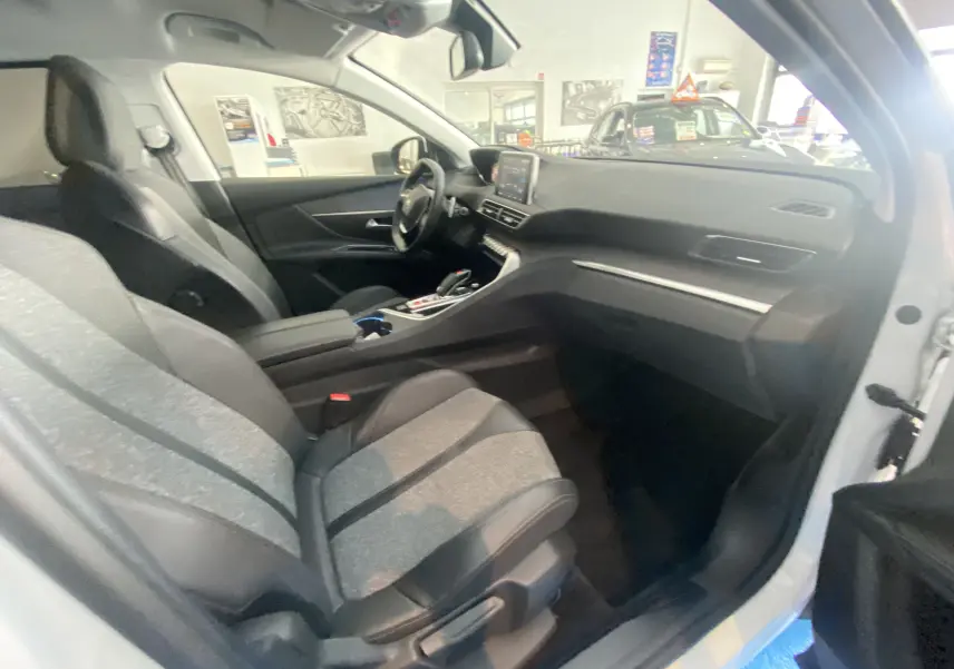 Intérieur avant droit d'un Peugeot 5008 blanc Blanquise, sièges gris tissu et cuir, tableau de bord moderne avec écran tactile.