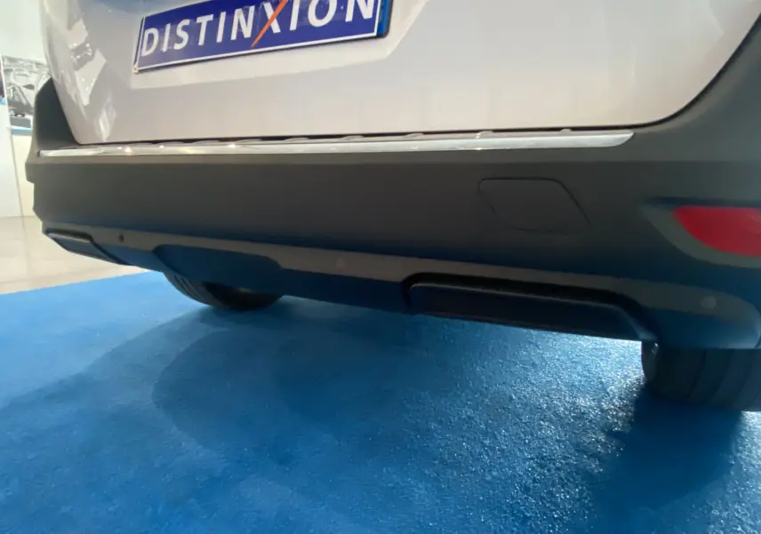 Gros plan sur le pare-chocs arrière blanc du Peugeot 5008 avec attelage de remorque neuf visible dessous.
