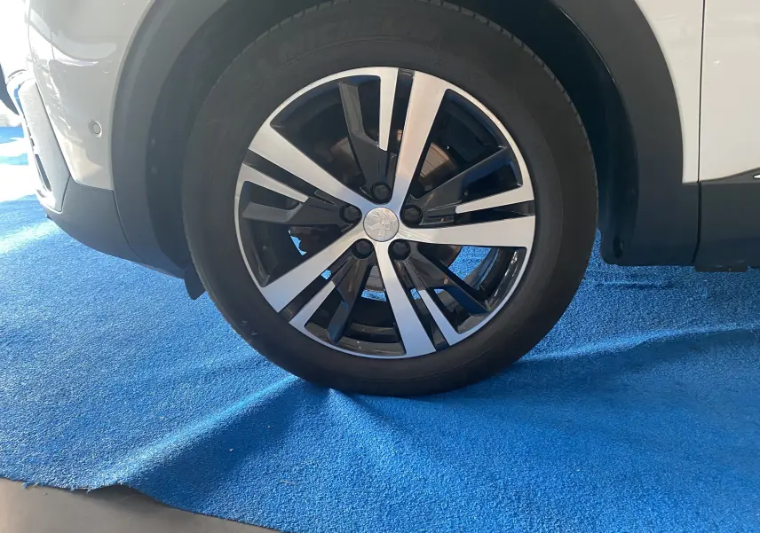 Gros plan sur la roue avant droite blanche du Peugeot 5008 II avec jante alliage bicolore et pneu Michelin neuf.
