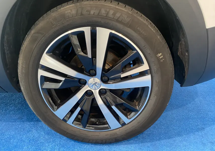 Gros plan sur la roue avant droite du Peugeot 5008 blanc, jante alliage bicolore et pneu Michelin neuf