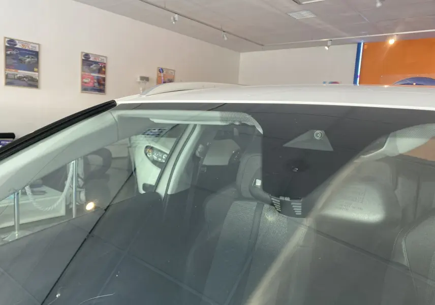 Vue rapprochée du pare-brise avant gauche d'un Peugeot 5008 blanc blanquise en showroom.