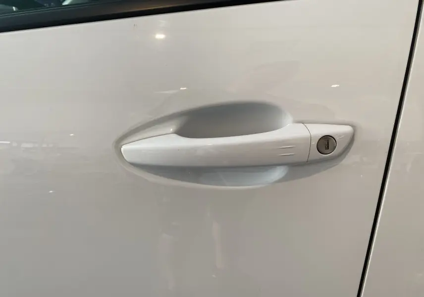 Poignée de porte blanche côté gauche d'un Peugeot 5008 II, avec serrure intégrée visible en gros plan.