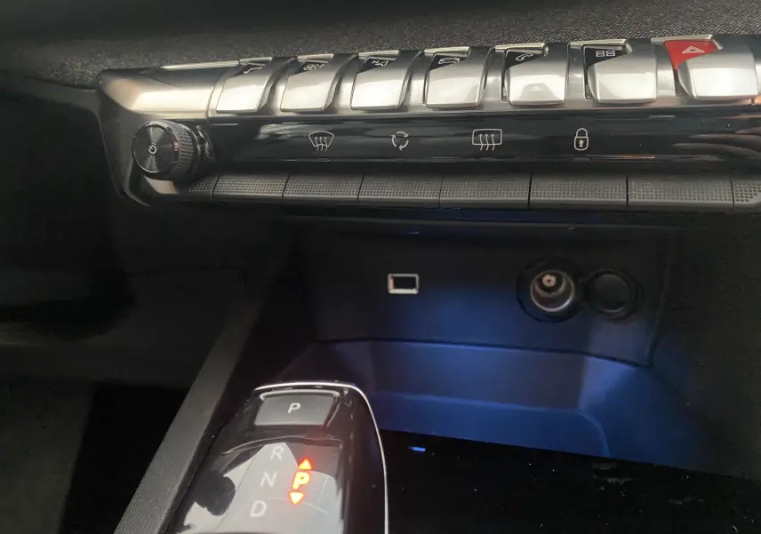 Gros plan sur la console centrale du Peugeot 5008 blanc, montrant la boîte auto et les commandes de climatisation.
