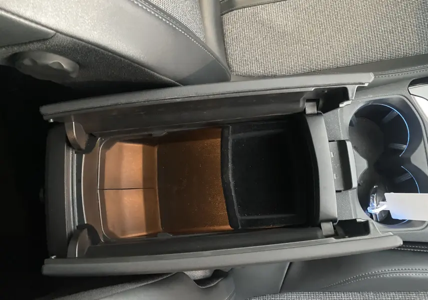 Vue plongeante sur le rangement central noir entre les sièges avant d'un Peugeot 5008 blanc Blanquise.