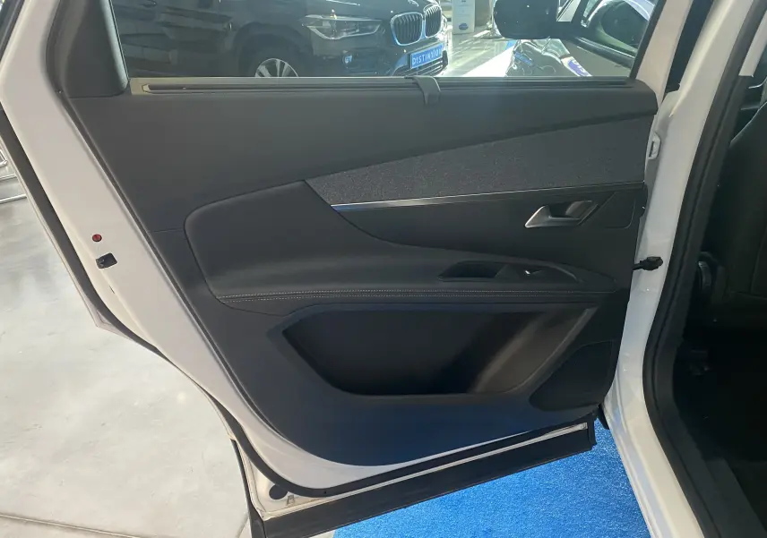 Porte arrière gauche ouverte d'un Peugeot 5008 blanc, intérieur noir avec garniture tissu et cuir.