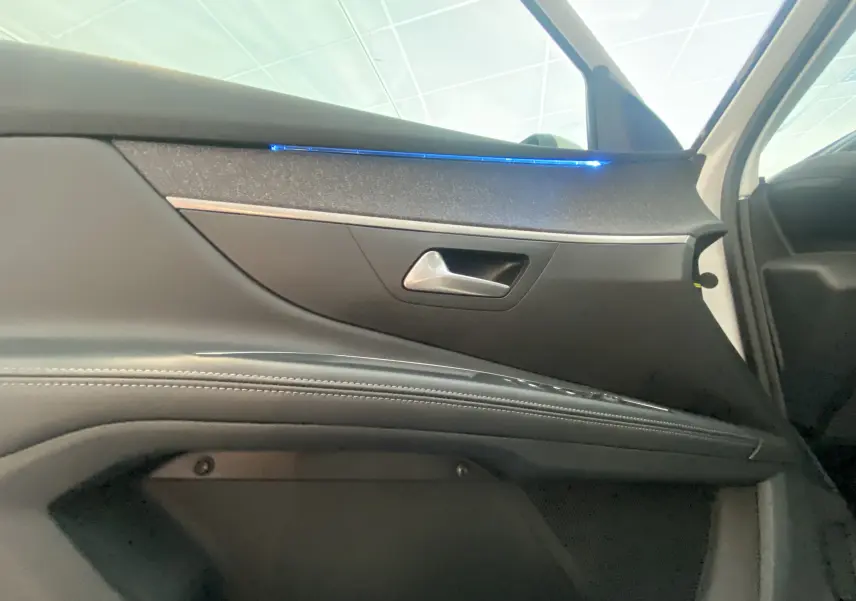 Détail de la porte avant droite du Peugeot 5008 blanc avec éclairage d'ambiance bleu et garniture noire.