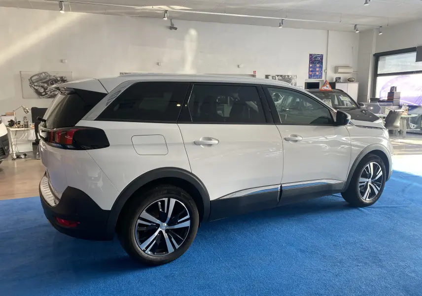 Peugeot 5008 blanc blanquise vu de profil côté droit, avec attelage de remorque et jantes noires et argentées.