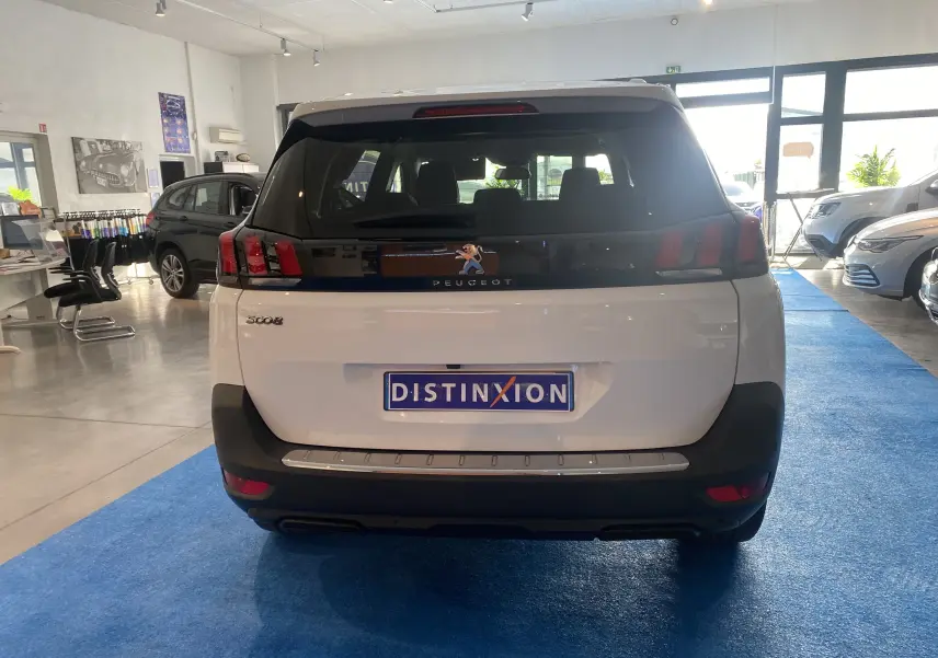Vue arrière d'un Peugeot 5008 blanc Blanquise dans un showroom, avec plaque Distinxion visible.