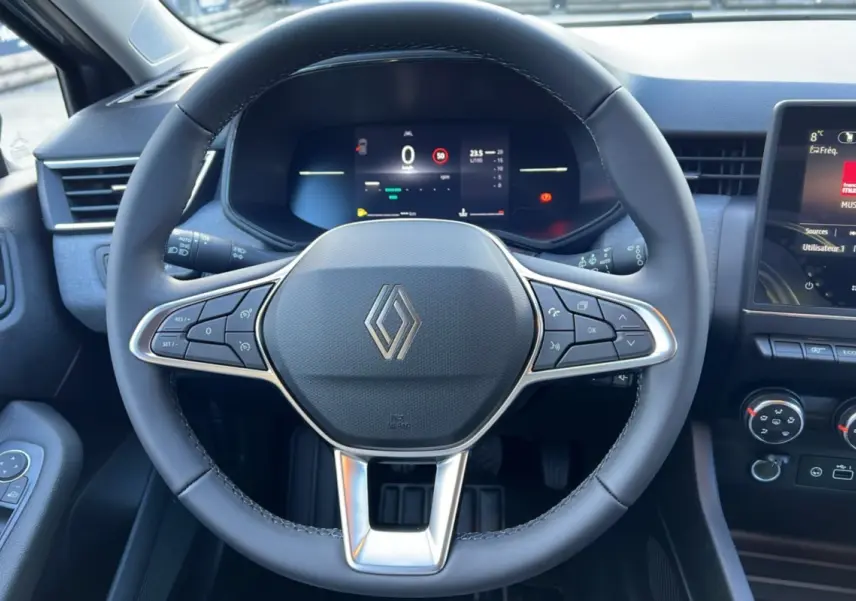 Vue intérieure centrée sur le volant du Renault Clio 2025 gris schiste avec commandes intégrées et tableau de bord digital.