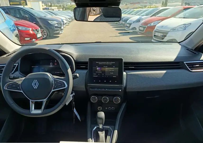 Vue intérieure frontale du tableau de bord et volant de la Renault Clio gris schiste 2025 avec écran tactile central et boîte auto.