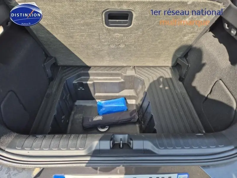 Coffre ouvert du Ford Puma 1.0 EcoBoost gris, montrant le rangement sous plancher avec trousse de secours bleue.