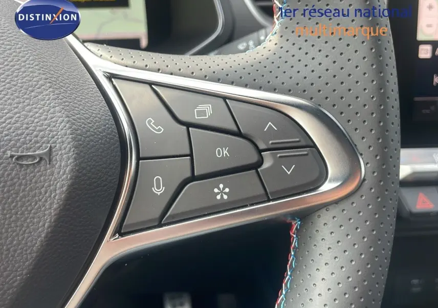 Gros plan sur les commandes multifonctions au volant en cuir perforé noir du Renault Captur E-Tech hybride 2025.