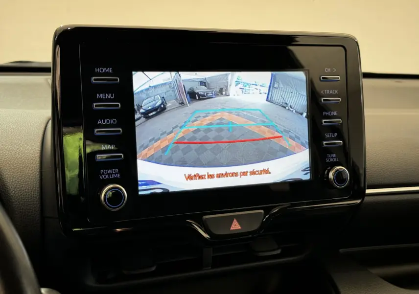 Écran tactile central montrant la caméra de recul avec guidage sur Toyota Yaris hybride blanche, vue intérieure frontale.