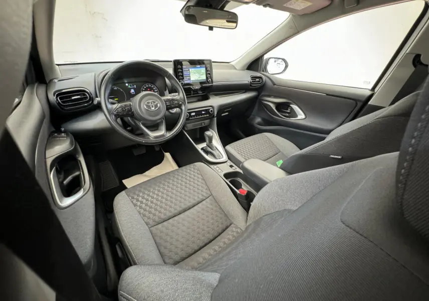Vue intérieure avant droite de la Toyota Yaris hybride 2022, montrant le tableau de bord avec écran tactile et volant multifonctions.
