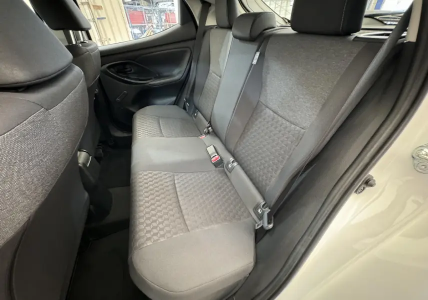 Vue intérieure côté droit des sièges arrière gris de la Toyota Yaris hybride blanche 2022 avec porte ouverte.
